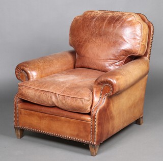 A club style armchair upholstered in brown leather, raised on square tapered supports with stud work decoration 85cm h x 66cm w x 79cm d 
