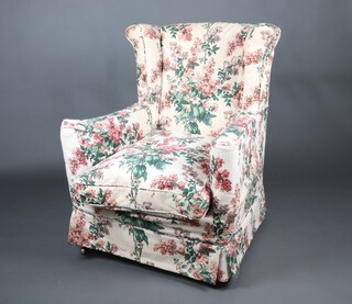 An Edwardian winged armchair upholstered in floral patterned material, raised on square tapered supports with brass casters 94cm h x 77cm w x 73cm d 