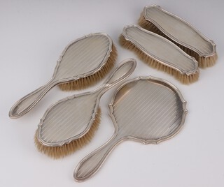 A silver backed 6 piece engine turned dressing table set comprising hand mirror, 2 hair brushes, 2 clothes brushes and a comb, Birmingham 1946 