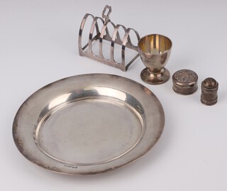 A circular silver dish Sheffield 1928 18cm, a 5 bar toast rack, egg cup, trinket box and pepper, 324 grams 