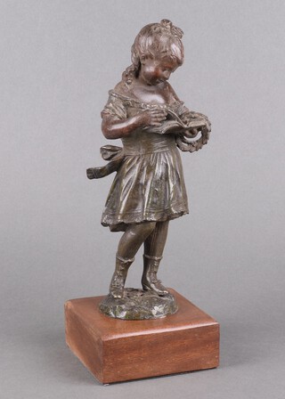 A Victorian spelter figure of a standing girl with book and wreath, raised on a mahogany case 27cm 