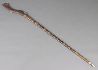 A 19th Century native matchlock gizelle with 132cm barrel, brass banding, complete with ram rod, the butt carved with floral pattern 