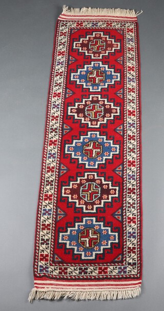 A red, blue and black ground Afghan runner with 6 stylised octagons to the centre within a multi row border 171cm x 52cm 