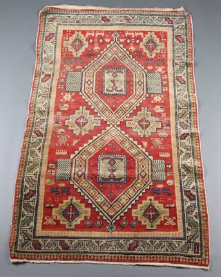 A green and tan ground Caucasian style rug with 2 stylised diamond medallions to the centre within a multi row border 155cm x 92cm  