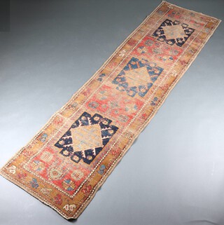 A brown, green and blue ground Caucasian style runner with 3 stylised diamond medallions to the centre within a multi row border 278cm x 74cm