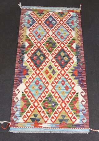 A tan, green, white and black ground Chobi Kilim runner with diamond design to the centre 150cm x 69cm 