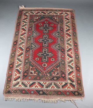 A red, green and brown ground Afghan rug with 3 medallions to the centre within a multi row border 193cm x 121cm 