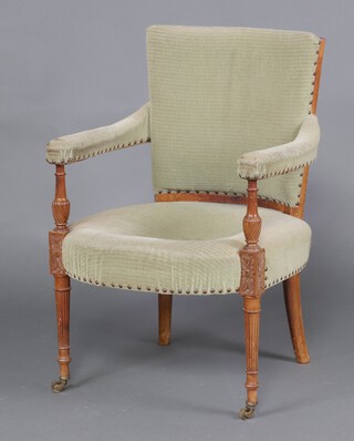 An Edwardian beech framed open arm chair, the seat and back upholstered in green material, raised on turned supports 