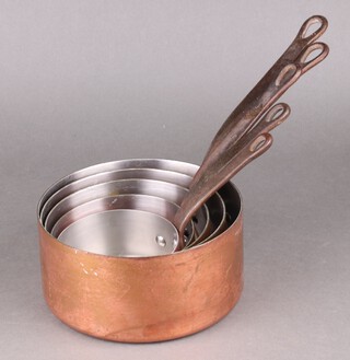 A set of 5 graduated copper saucepans with iron handles 