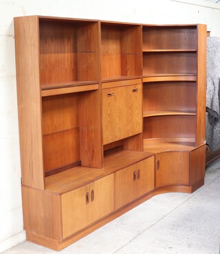 G-Plan, a large 1970's teak wall unit comprising cupboards, shelving, a fall front drinks cabinet with inbuilt lighting, together with a modern pine TV cabinet 240cm h x 200cm w