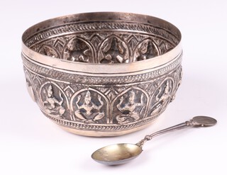 An Indian circular embossed white metal bowl decorated figures of a seated gnash 10cm together with a silver spoon