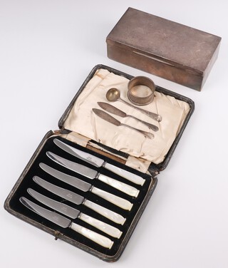 A silver cigarette box with engine turned decoration London 1947, 5cm x 17cm x 9cm (splits and dents), a Georgian silver mustard spoon, 2 silver butter knives and a silver napkin ring, weighable silver 46 grams, together with a set of 6 tea knives with mother of pearl handles 