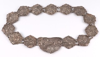 An Edwardian Art Nouveau silver belt, the buckle decorated reclining maidens, the links with embossed floral decoration, Birmingham 1903, marked W & H, the reverse marked Corkes Patent no.4956703, 178 grams gross