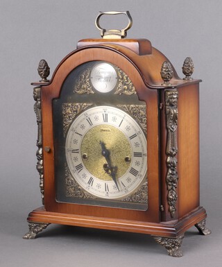 Hermle, an 8 day chiming bracket clock with 19cm arched brass dial, silver chapter ring, the back plate marked 75 Bulova Watch Comp. Inc., compete with key, contained in an arch shaped mahogany case with gilt metal finials 34cm h x 29cm w x 14cm d 