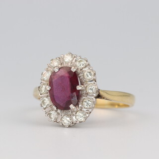 An 18ct yellow gold ruby and diamond cluster ring, the central oval ruby approx 0.96ct, the diamonds 0.42ct, size P 1/2, 4.48 grams 