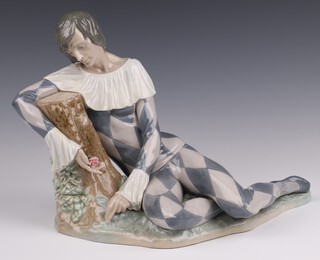 A Lladro figure of a reclining harlequin by a tree stump with rose, 5128, base impressed E-11M 25cm x 37cm 