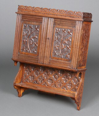 A Victorian carved oak wall cabinet with arcade shaped cornice, the interior fitted a drawer enclosed by carved panelled doors with ivy decoration above a recess, carved with roundels and fitted a shelf 82cm h x 63cm w x 20cm d 