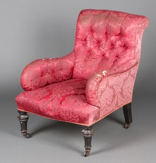 A Victorian armchair upholstered in red floral patterned material, raised on turned and fluted ebonised supports 83cm h x 64cm w x 65cm d  