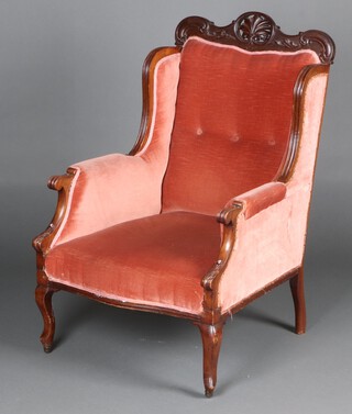An Edwardian show frame mahogany winged armchair, the seat of serpentine outline, upholstered in rose pink material, raised on cabriole supports 101cm h x 63cm w x 65cm d 