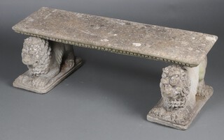 A well weathered concrete garden  bench supported by lions 42cm h x 126cm w 