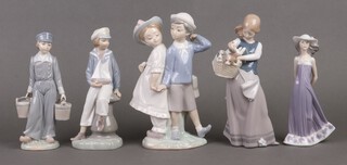 A collection of Lladro figures to include standing girl with basket of puppies 1311 23cm, standing boy and girl 1.15M5, boy with yacht 94, boy with 2 pails 53 and standing girl 564 