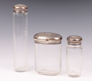 Two faceted glass pin jars 16cm and 9cm with silver tops and an oval ditto 10cm (silver top dented) London 1916, all monogrammed 