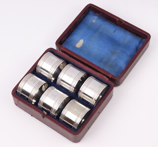 A set of 6 Victorian silver plated napkin rings with armorial decoration and numbered 1-6, contained in a red leather case (hinge a/f)