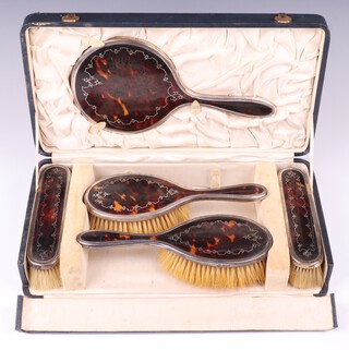 A silver and tortoiseshell pique ware 5 piece dressing table set comprising hand mirror, 2 hair brushes and 2 clothes brushes, London 1924 by Mappin & Webb, in original case