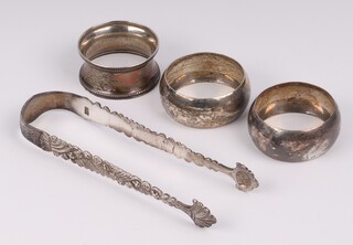 A pair of Georgian silver sugar tongs (possibly repaired) and a pair of Continental silver napkin rings marked 933, 85 grams 