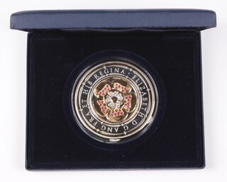 A Westminster Mint 5oz 999 silver commemorative coin with obverse design of a Tudor Rose in gold plate decorated rubies and diamonds, mint sealed in blue plush fitted case with COA