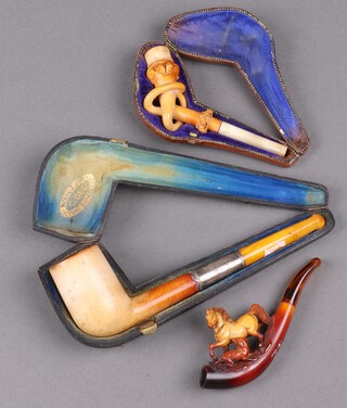 A Meerschaum pipe with "amber" mouthpiece, a carved Meerschaum cheroot holder with horn mouthpiece boxed and a carved 1 other decorated a horse  