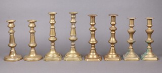 Three pairs of 19th Century brass candlesticks with ejectors and square bases 26cm x 25cm x 23cm and a circular pair of brass candlesticks 22cm (misshapen) 