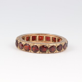 A 9ct yellow gold garnet set eternity ring, size H 1/2, 2.4 grams 