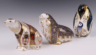 A Royal Crown Derby Sue Rowe Exclusive Signature limited edition paperweight for Grovers of Sidmouth in the form of a polar bear, the base with gold stopper 10cm, a Royal Crown Derby Imari pattern paperweight of a walrus, base with gold stopper 21, 11cm, ditto penguin LXI 12cm, all boxed
