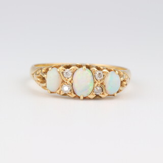 An 18ct yellow gold dress ring set 3 oval opals supported by 4 small diamonds, size P 1/2, 2.6 grams 