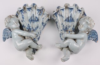 A pair of 19th Century blue and white faience wall pockets in the form of cherubs supporting shells 27cm, the reverse decorated a standing cockerel