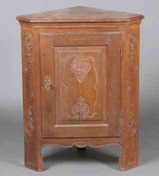 An 18th/19th Century carved oak Continental corner cabinet enclosed by a panelled door, raised on bracket feet 100cm h x 80cm w x 57cm d 