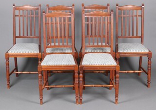 A set of 6 Art Nouveau walnut stick and rail back dining chairs with upholstered seats, raised on turned supports with H framed stretcher, base marked W B 