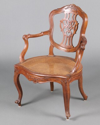 A Continental carved and pierced hardwood open arm salon style chair with pierced slat back, the seat of serpentine outline and with woven cane seat 90cm h x 59cm w x 51cm d 