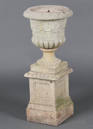 A well weathered concrete garden  urn with lobed decoration, raised on a separate square base 80cm h x 36cm diam. 