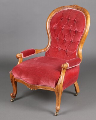 A Victorian carved bleached walnut show frame open arm chair, in rose pink buttoned material, on cabriole supports with brass casters 95cm h (a/f)