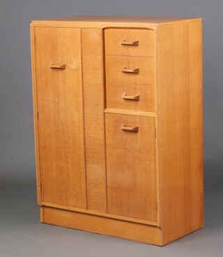 A G-Plan mid-century light oak combination wardrobe with hanging space, flanked by 3 long drawers above cupboard, enclosed by panelled doors 121cm h x 87cm w x 45cm d (sun bleached  in places)