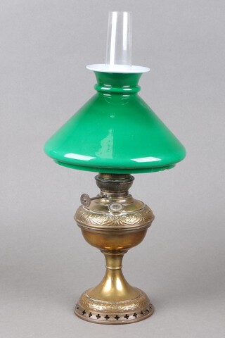 An embossed brass oil lamp with chimney and an opaque green glass shade (chipped) 46cm h