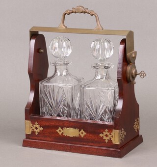 A mahogany and brass mounted 2 bottle tantalus fitted 2 cut glass decanters  