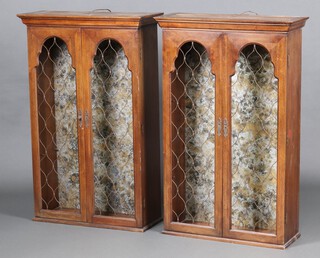 The Davis Cabinet Company Nashville Tennessee, a  pair of walnut finished display cabinets enclosed by grilled panelled doors 111cm h x 72cm w x 27cm d 