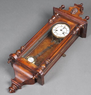 A regulator style wall clock with enamelled dial, Roman numerals and grid iron pendulum, contained in a walnut case 