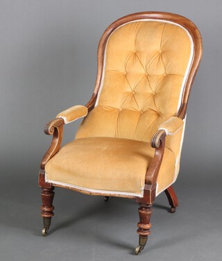 A William IV mahogany show frame button back open armchair, upholstered in mustard coloured material, on turned supports, brass casters 116cm h