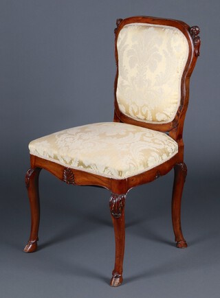 A Continental carved walnut salon chair, the shoulders carved angels heads, with upholstered seat and back, raised on cabriole supports with hoof feet 98cm h x 55cm w x 47cm d 