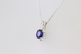 An 18ct white gold, sapphire and diamond surround pendant, hung on an 18ct white gold chain, 3.5 grams 