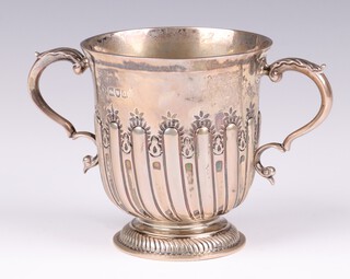 An Edwardian embossed silver twin handled cup with demi-reeded decoration, London 1899, marks rubbed 226 grams 